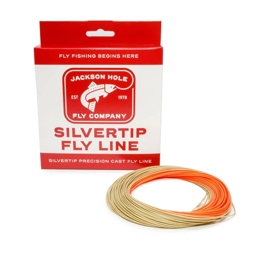 A coil of tan fly line with orange tips (Silvertip Weight Forward Fly Line With Welded Loop, 4–6WT) from Jackson Hole Fly Company sits before a red and white box featuring a fish graphic and trout fly line text.