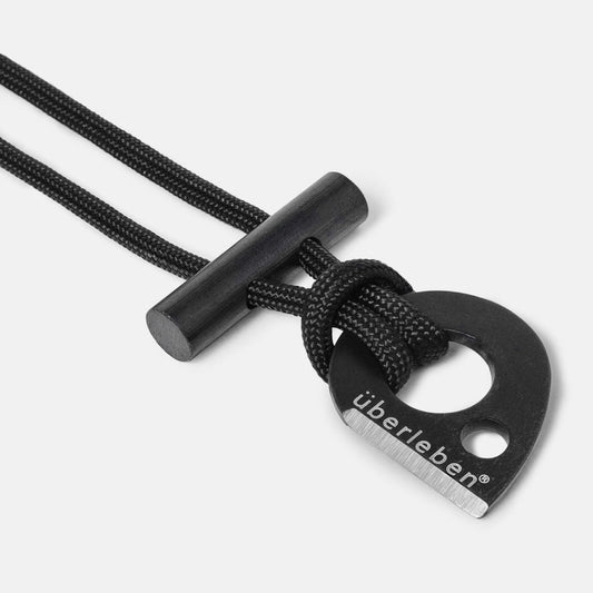 Close-up of the Überleben Leicht – Wearable Fire Starter by Überleben, a black tool with a metal striker engraved überleben, attached to a black cord and featuring a cylindrical micro ferro rod for creating sparks.