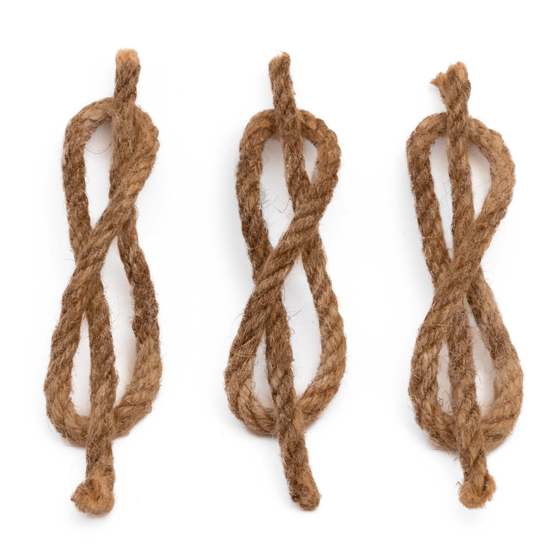 Three pieces of brown waterproof hemp wick from the Überleben Tindår Wick & Bellow Kit are arranged vertically in loose figure-eight shapes on a white background.